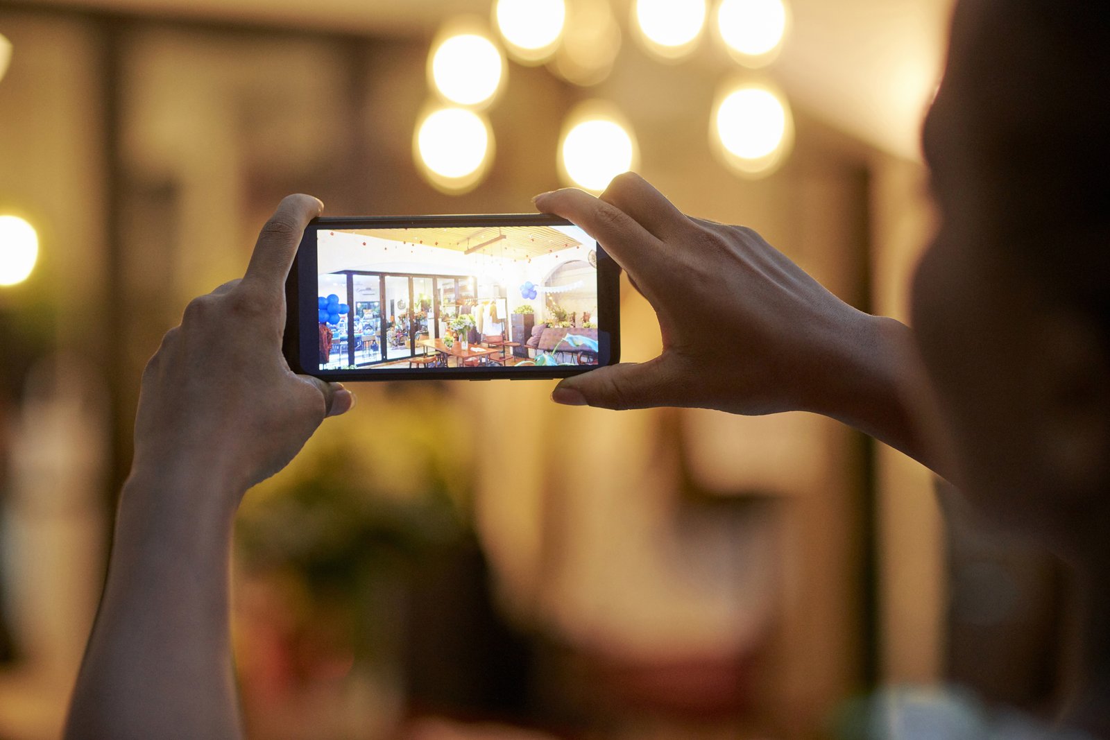 A small business owner in Oklahoma taking a photo of their storefront with a phone in daylight