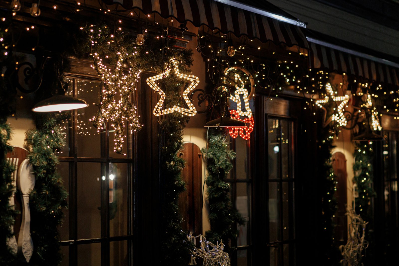 A small business owner in Oklahoma stringing simple string lights across a storefront window in early fall, sleeves rolled up, getting ready ahead of the holiday rush.