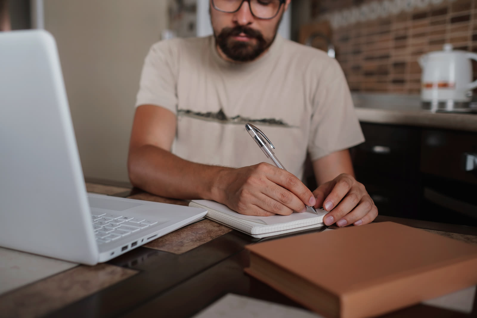 Small business owner writing website copy at a desk with a notebook and laptop